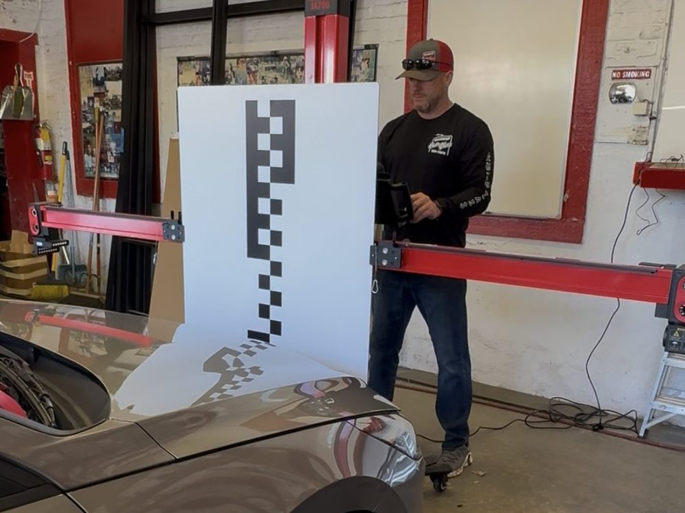 Newburgh Auto Glass technician performing ADAS camera calibration with a target board