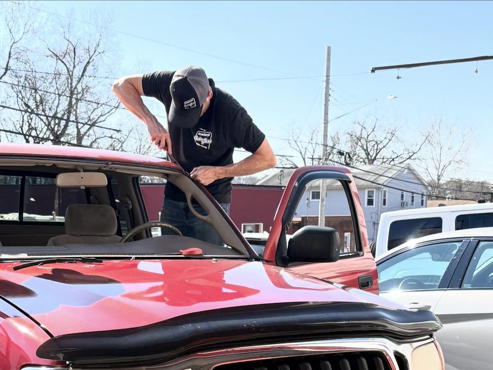 Newburgh Auto Glass technician replacing the windshield on a red Toyota Tacoma
