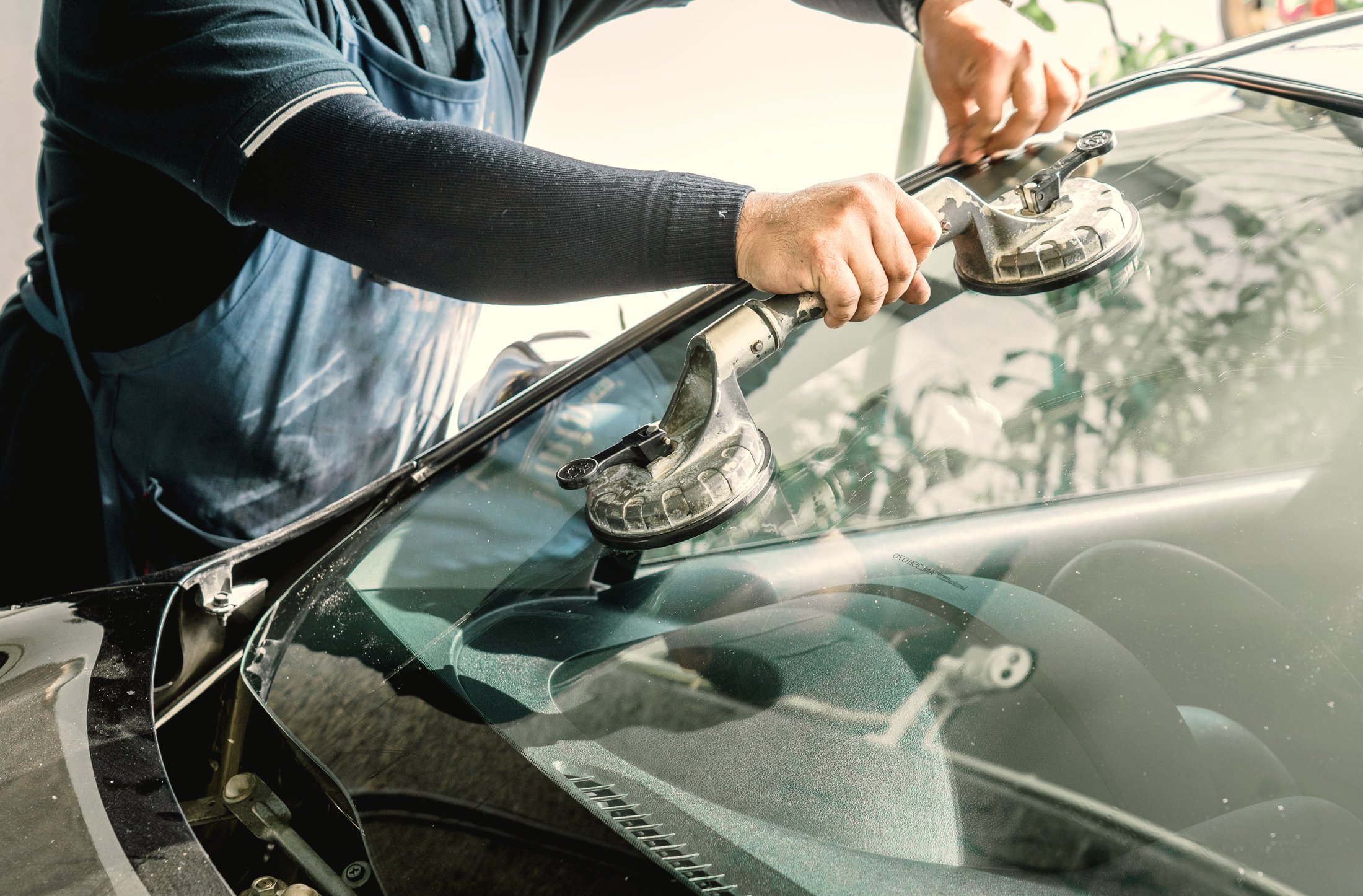Newburgh Auto Glass technician installing a windshield on a dark vehicle